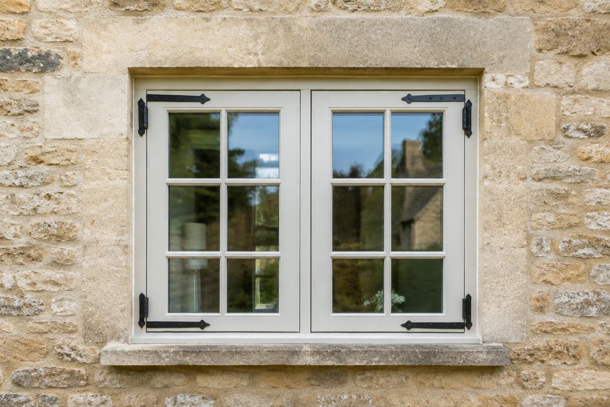 Traditional painted timber casement cottage window in a Cotswold stone wall after repair